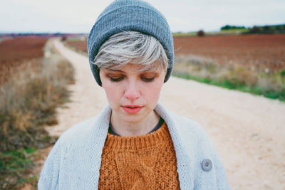 Close-up of woman wearing knit hat while standing on dirt road