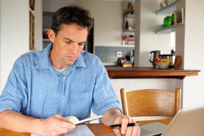 Businessman doing paperwork at desk in home