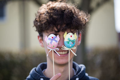 Close-up of teenage boy holding easter egg in front of face