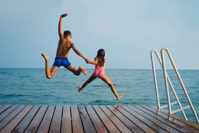 Kids jump to the water, having fun on vacation