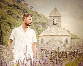 Young man standing by flowering plants against senanque abbey