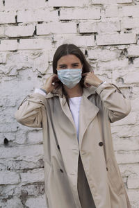 Portrait of young woman standing against wall