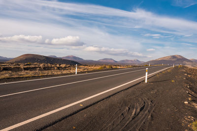 Road leading towards mountains against sky