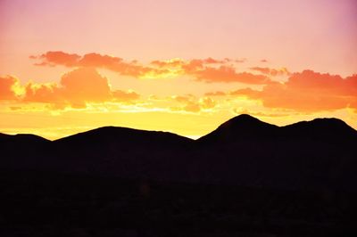 Scenic view of silhouette mountains against orange sky