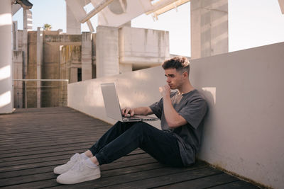 Full length of young man sitting on mobile phone