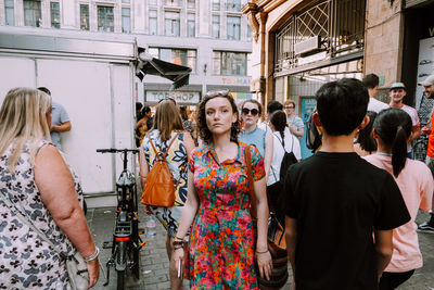 Rear view of people standing on street in city