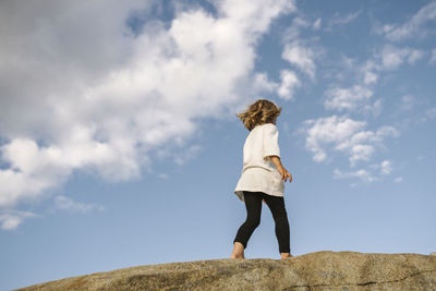 Low angle view of girl walking on rocks barefoot