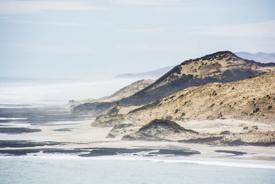 Scenic view of mountains by sea against sky