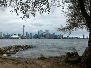 Sea and buildings in city against sky