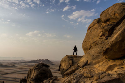 People standing on rock against sky