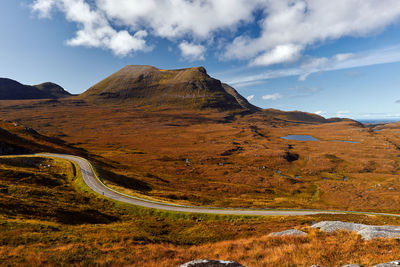 Scenic view of road by mountains against sky