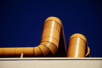 Low angle view of pipes on building against clear sky