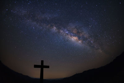 Low angle view of cross against sky at night