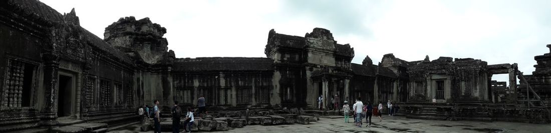 Tourists at historical building against cloudy sky