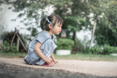 Side view of girl crouching on field