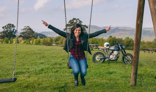 Portrait of smiling young woman sitting on swing 