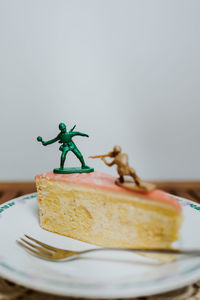 Two toy soldiers fighting on the top of a piece of cake about calories - close up white background