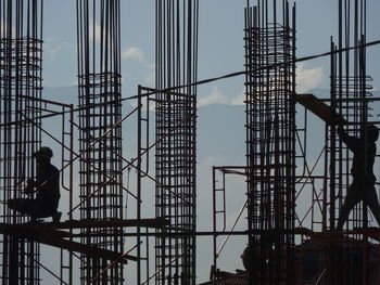 Silhouette people at construction site against sky