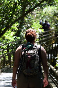 Rear view of woman standing against trees