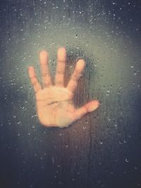 Close-up of hand on wet glass
