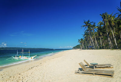 Deck chairs on beach against blue sky