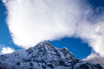 Low angle view of snowcapped mountains against blue sky