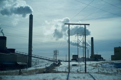 Low angle view of electricity pylon against sky during winter