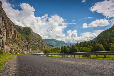 Scenic view of road by mountains against sky