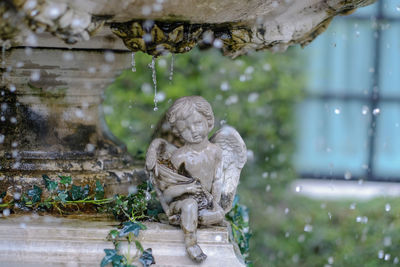 Statue by tree against building