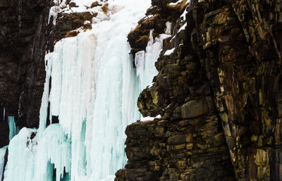 Scenic view of frozen cliff against sky during winter