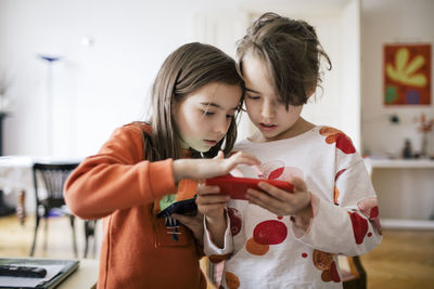 Sisters sharing smart phone at home