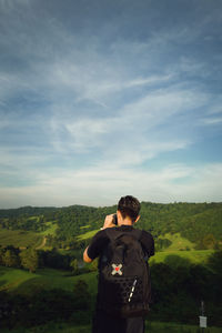 Rear view of woman standing on field against sky