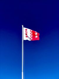 Low angle view of flag against clear blue sky