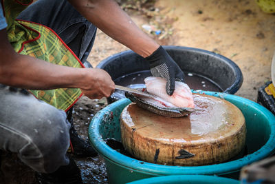 Midsection of man cutting fish in market