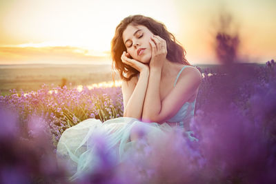 A beautiful young girl against the sunset and a beautiful sky in a lavender field. 