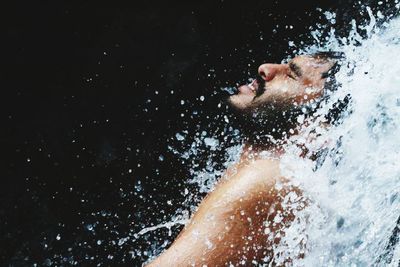 Man splashing water against black background