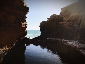 Rock formations by sea against sky