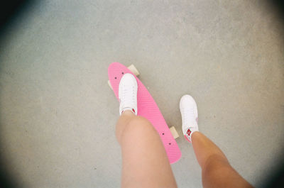 Low section of woman standing on pink shoes