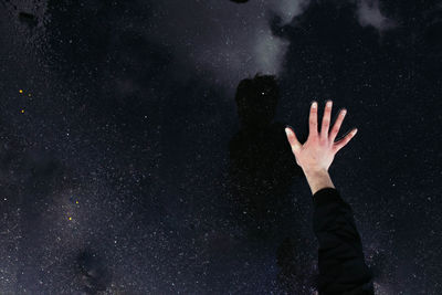 Close-up of hands against sky at night