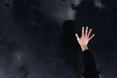 Cropped hand on puddle with reflection of star field