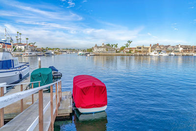 Red boat moored in sea against cloudy sky