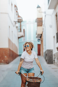 Portrait of young woman wearing sunglasses standing in city