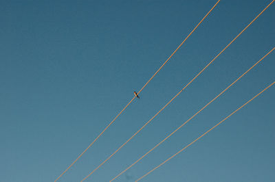 Low angle view of airplane flying against clear blue sky