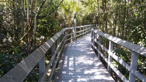 Footbridge over river against trees