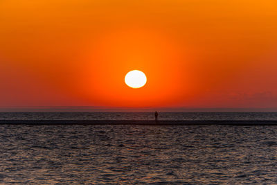 Scenic view of sea against orange sky