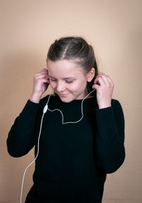 Young man using mobile phone against wall