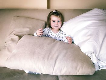 Cute child girl chilling on a sofa with pillow