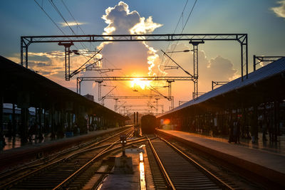 Railroad tracks against sky at sunset