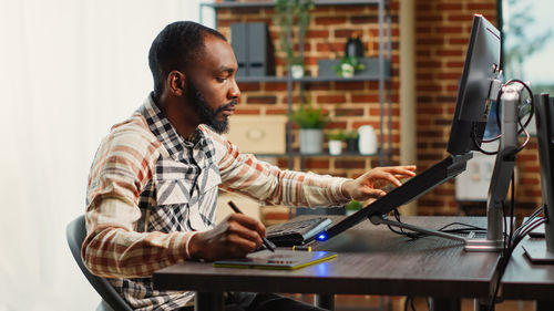 Side view of young woman using laptop at home