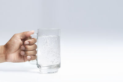 Hand holding glass of water against white background